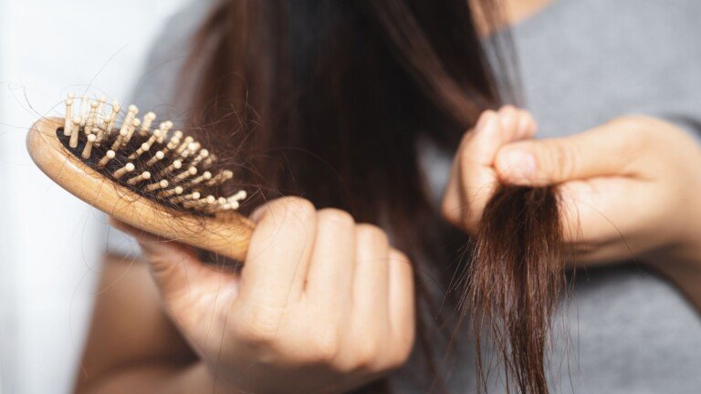 Woman with hair shedding visible on a hair brush
